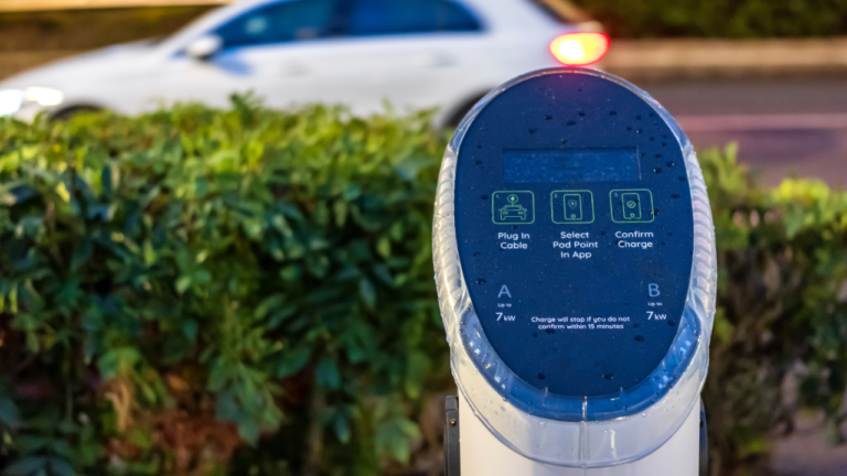 A EV charger next to a hedge